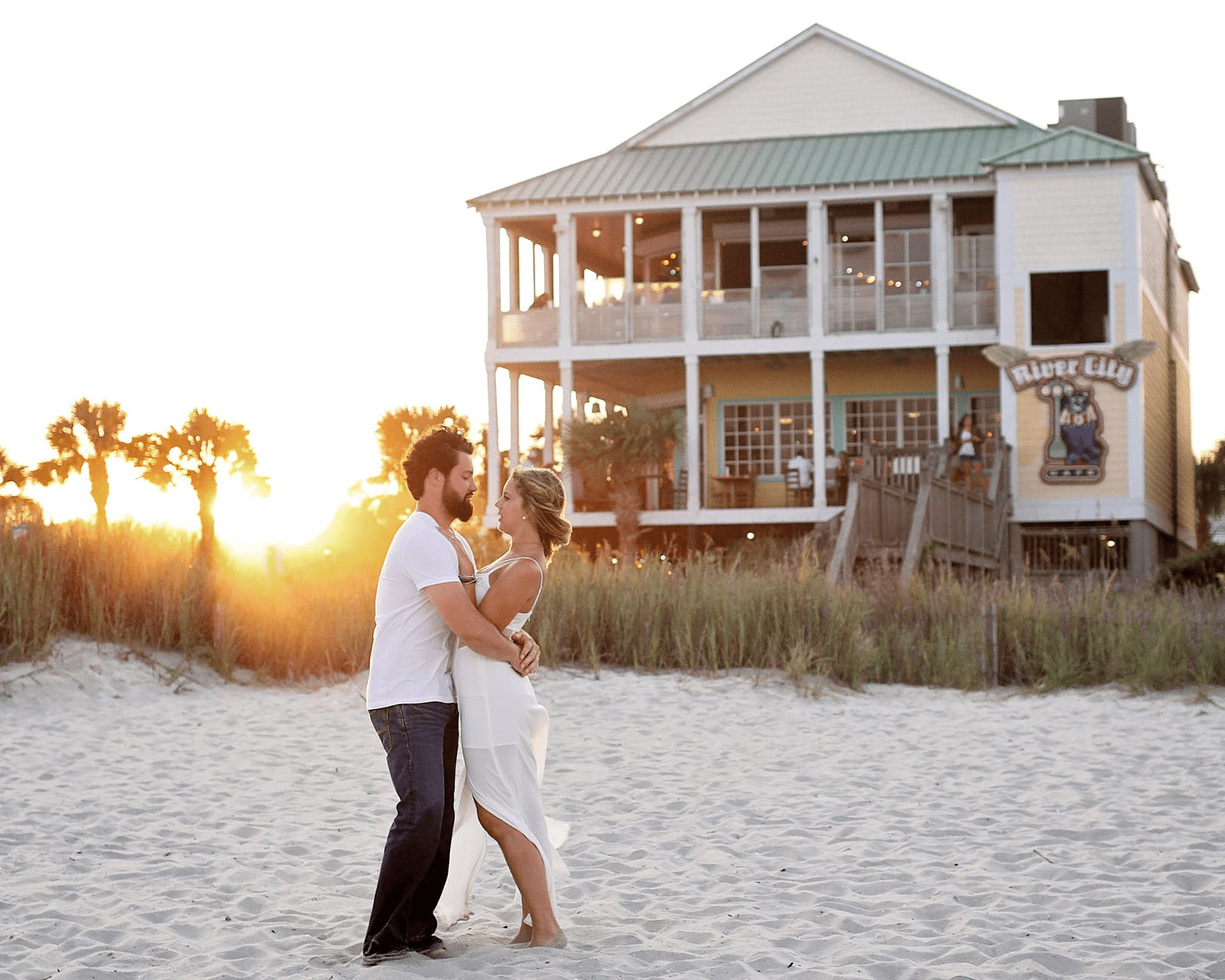 a man and a woman hugging outside a house by the beach
