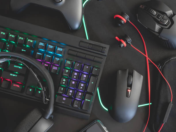 e-sport concept, top view a gaming gear, mouse, keyboard, joystick, headset, mobile joystick, in ear headphone and mouse pad on black table background.