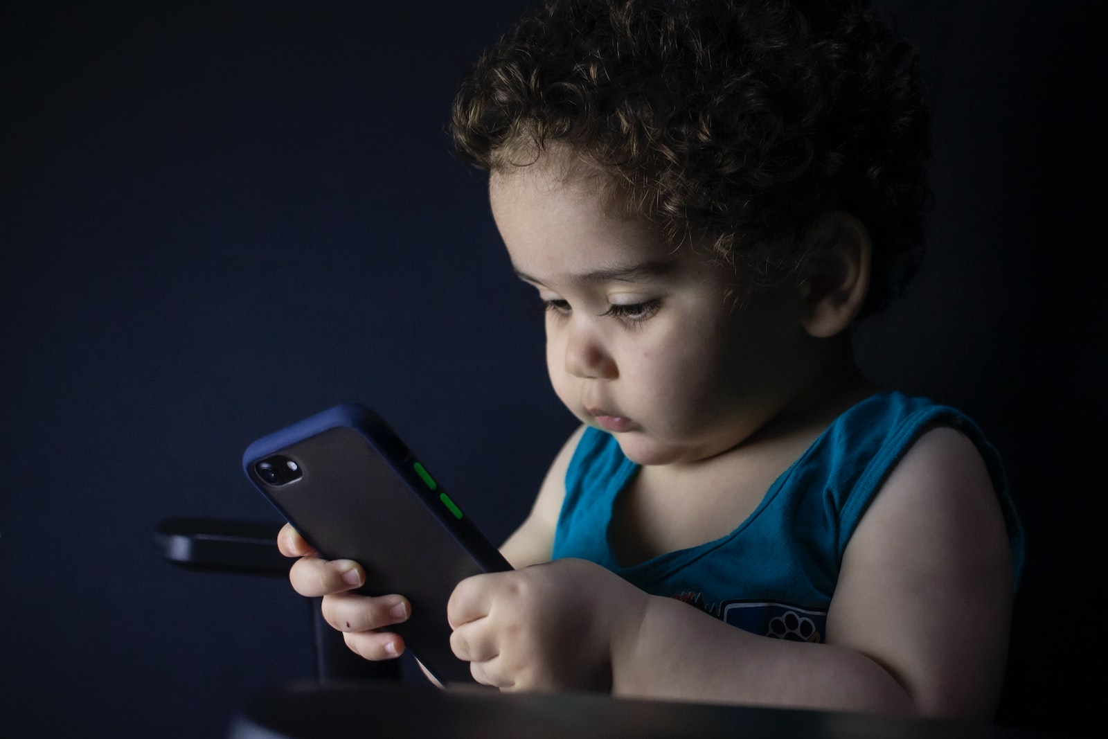 boy in blue tank top holding black iphone 5