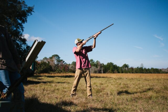 a man holding a rifle while standing in a field