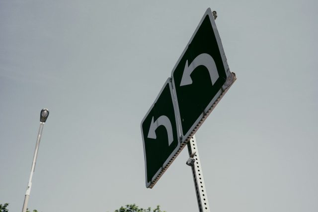 Green sign showing two white u-turn arrows